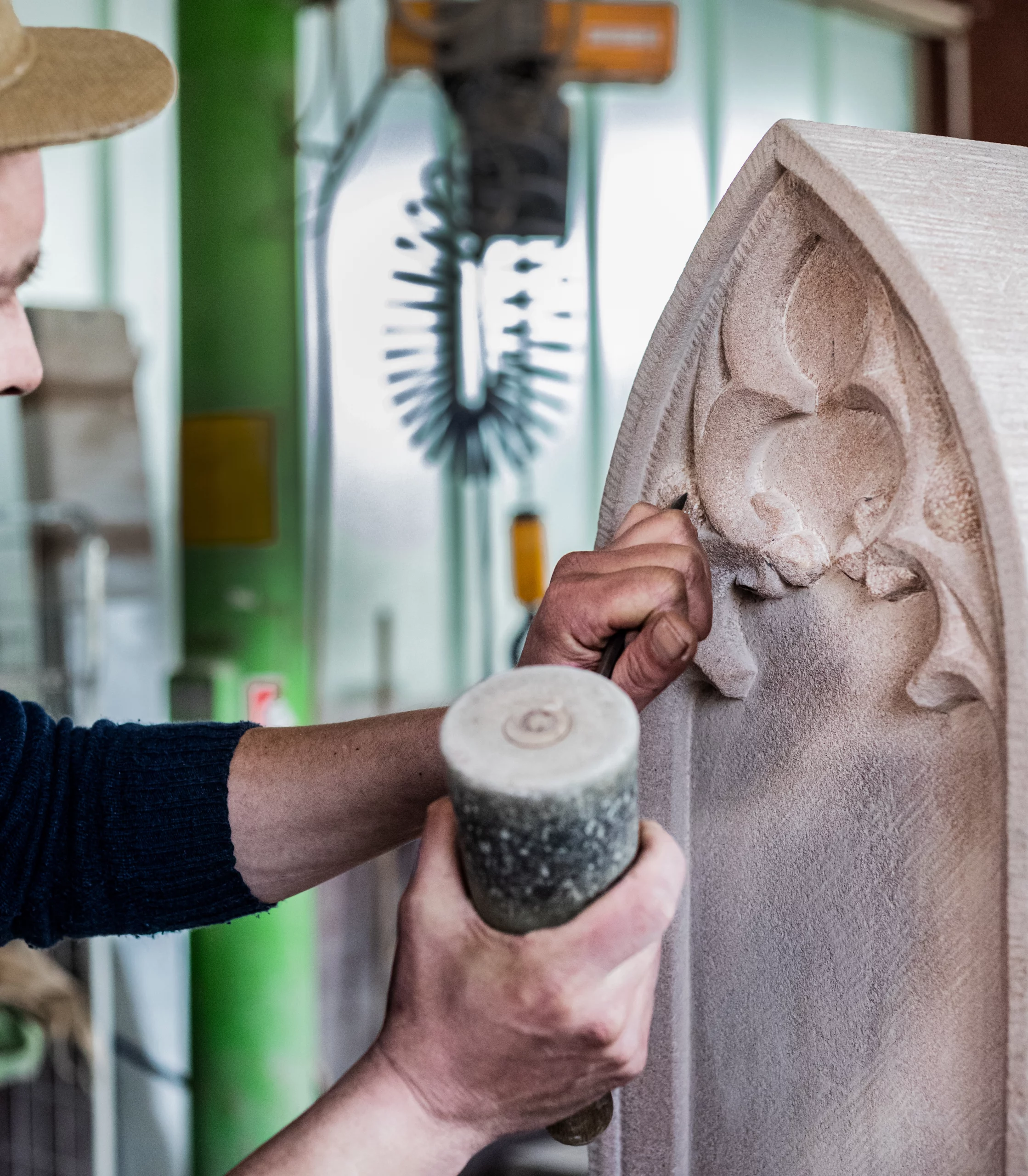 Es ist ein Handwerker beim meißeln in der Werkstatt abgebildet.