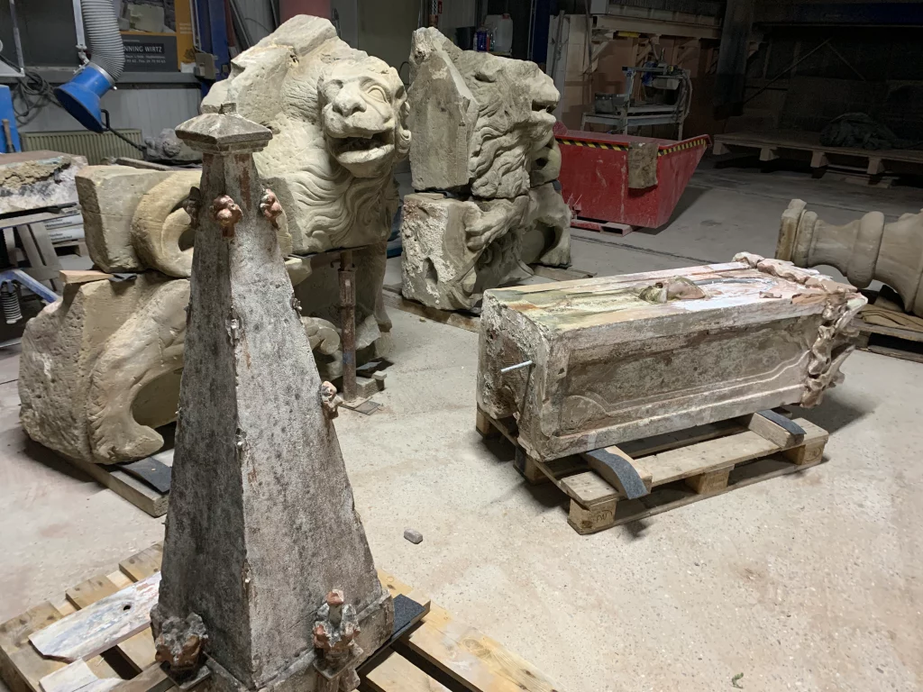 Zwei Bruchteile zweier Löwen Figuren werden in der Werkstatt restauriert.