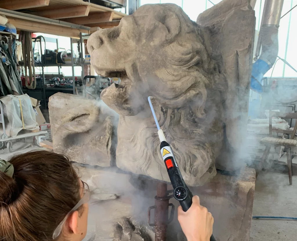 Ein Mitarbeiter ist an der Arbeit der Restauration einer Figur in der Werkstatt.