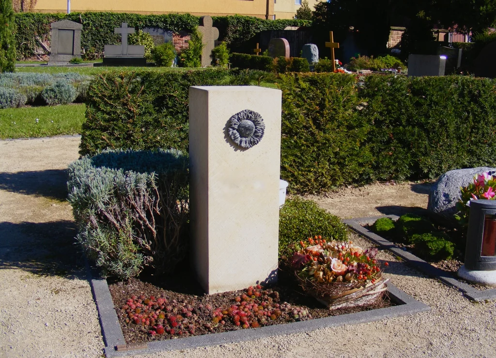 Ein heller Urnengrabstein mit Sonnenblumen Motiv.