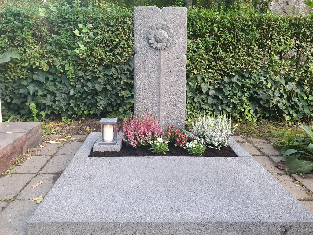 Ein Urnengrabstein mit dem Motiv einer Sonnenblume.