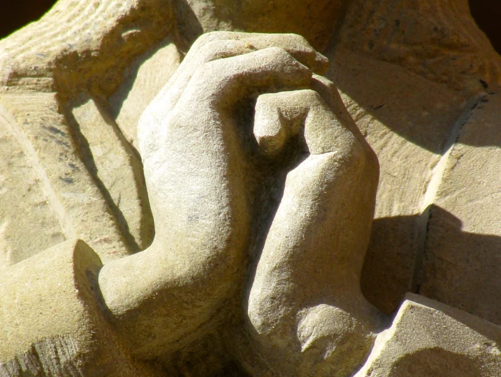 Nahaufnahme einer Statue mit zwei gefalteten Händen.