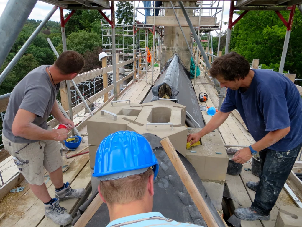 Aufnahme der Mitarbeiter während der Restaurierungsarbeiten auf einem Dach.