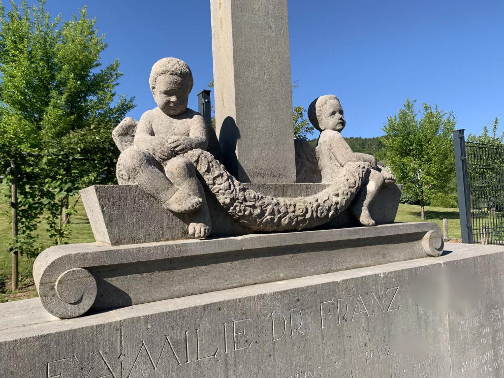 Es wird ein historisches Denkmal mit zwei aufsitzenden Stein-Figuren abgebildet.