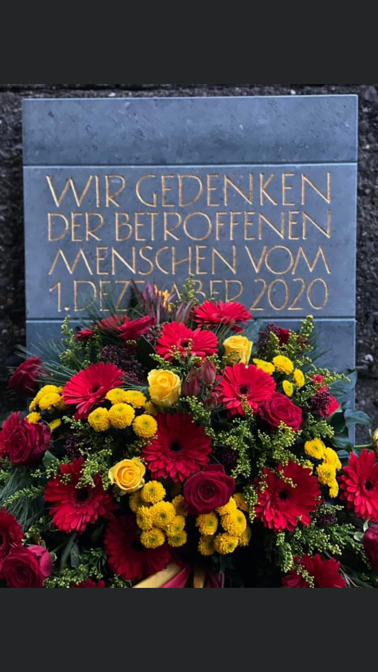 Die fertige Gedenktafel mit einem schönen, großen Blumenstrauss davor.