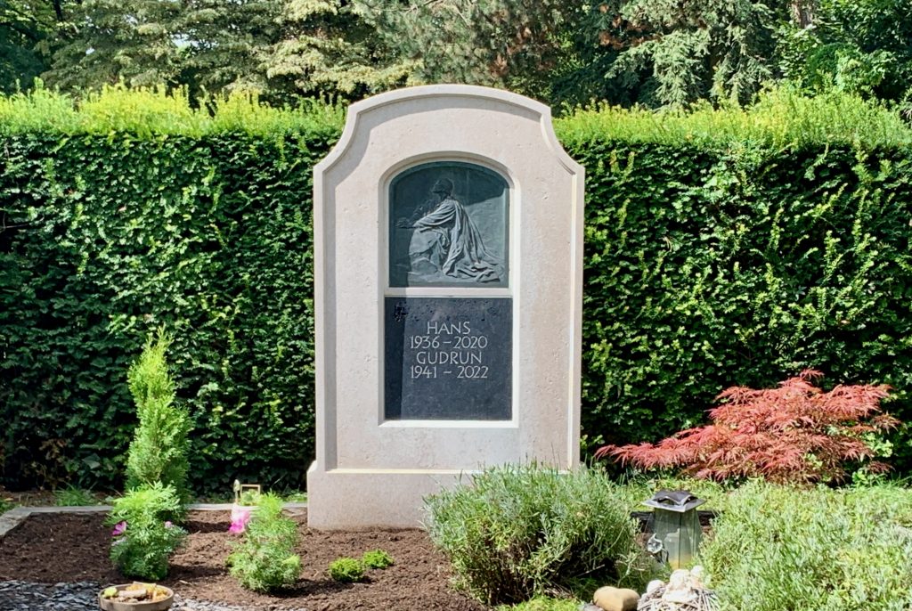 Ein Grabstein für Hans (1936-2020) und Gudrun (1941-2022) mit einem betenden Mann als Motiv.